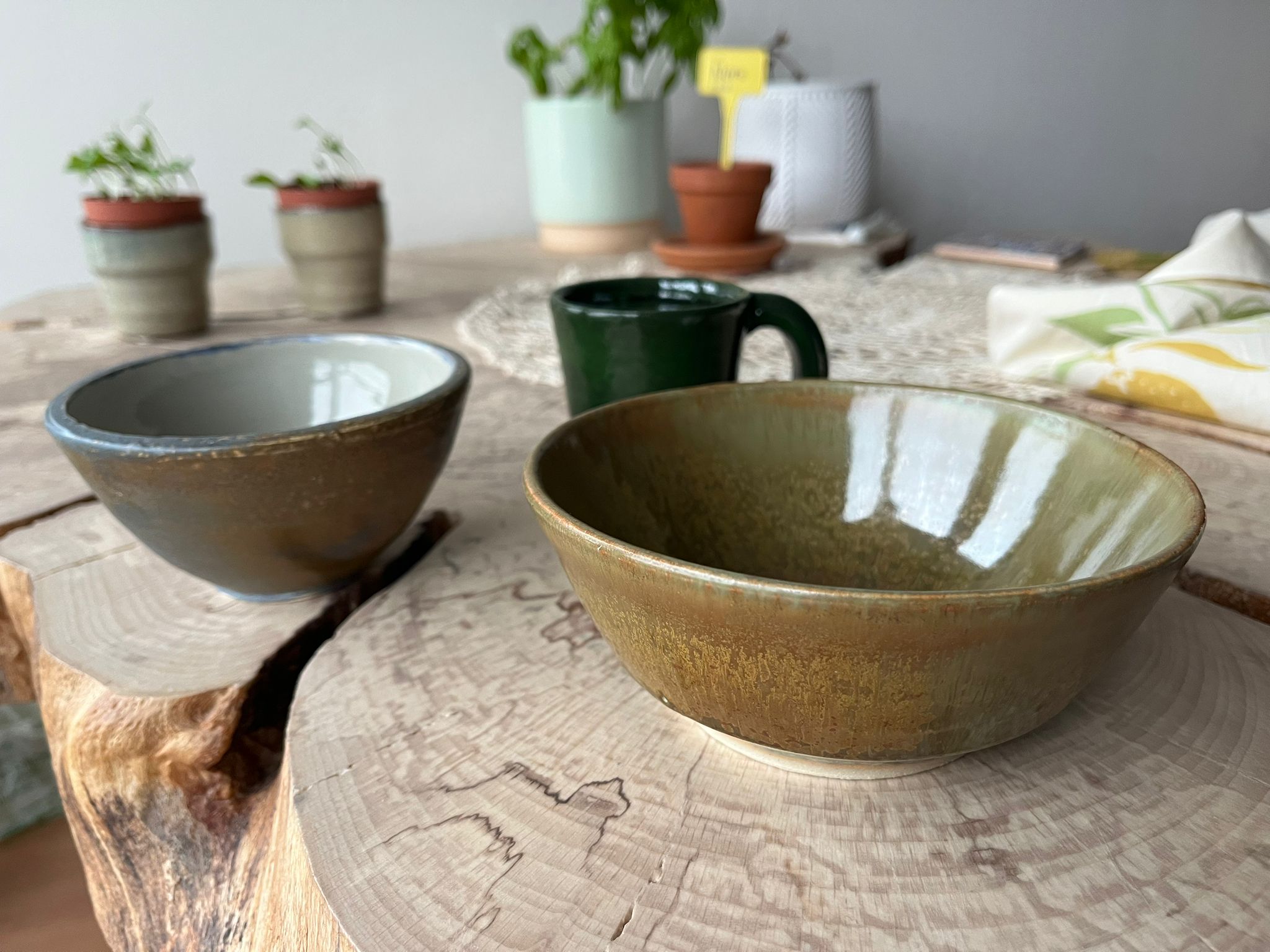 Glazed ceramic bowls and mug on wooden table made in pottery class