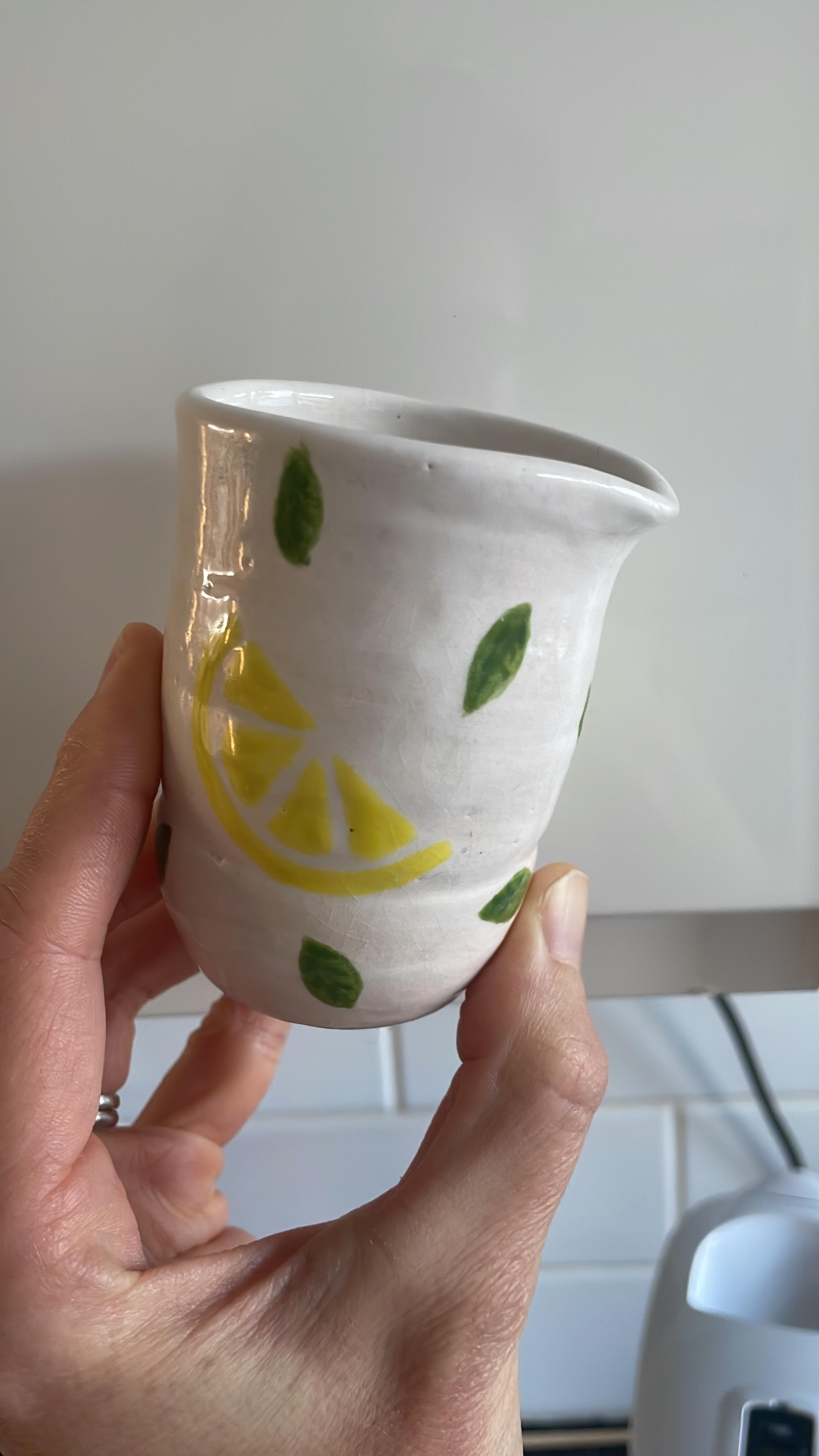 White ceramic cup with hand-painted lemon and leaf design