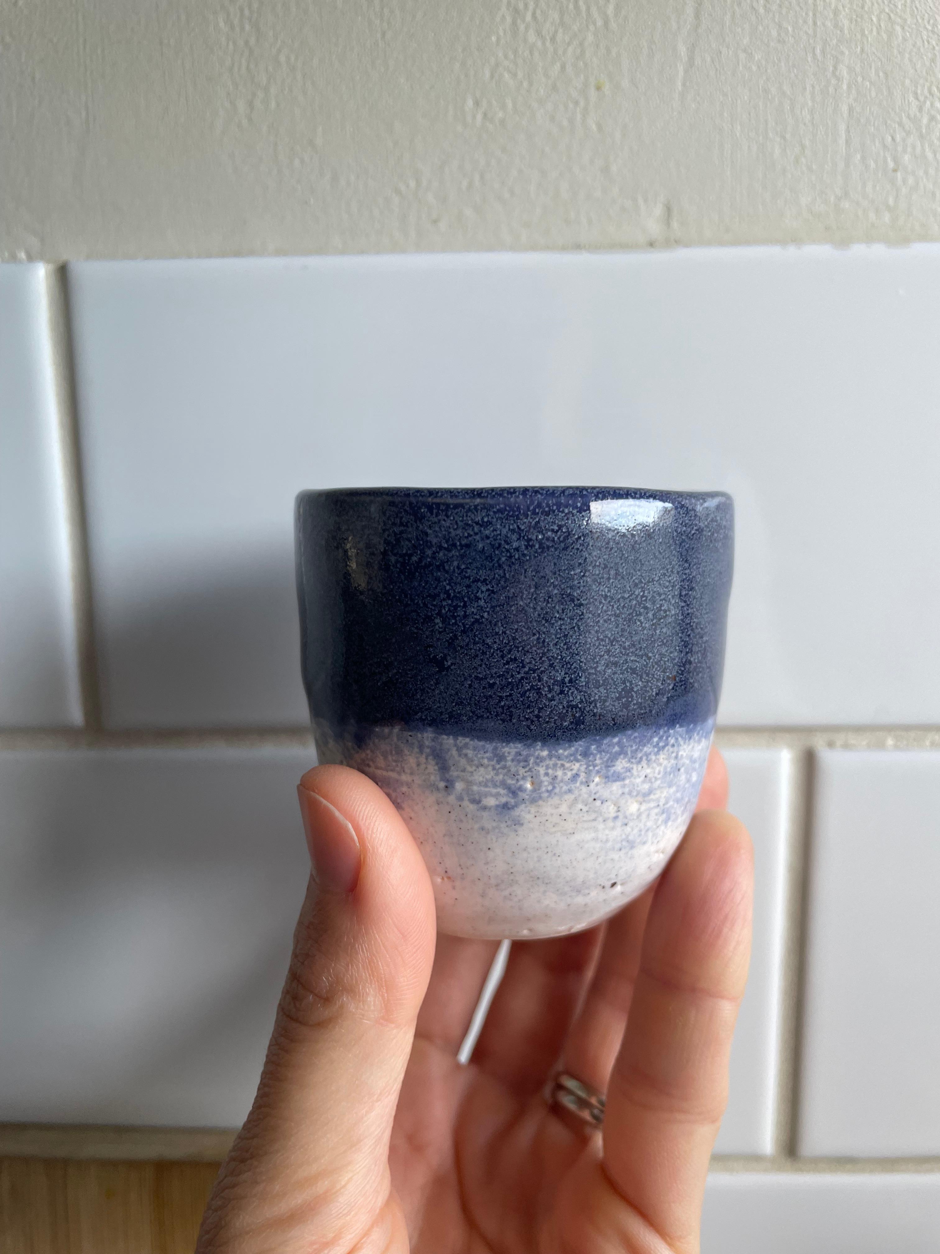 Blue and white glazed ceramic cup handmade at pottery workshop