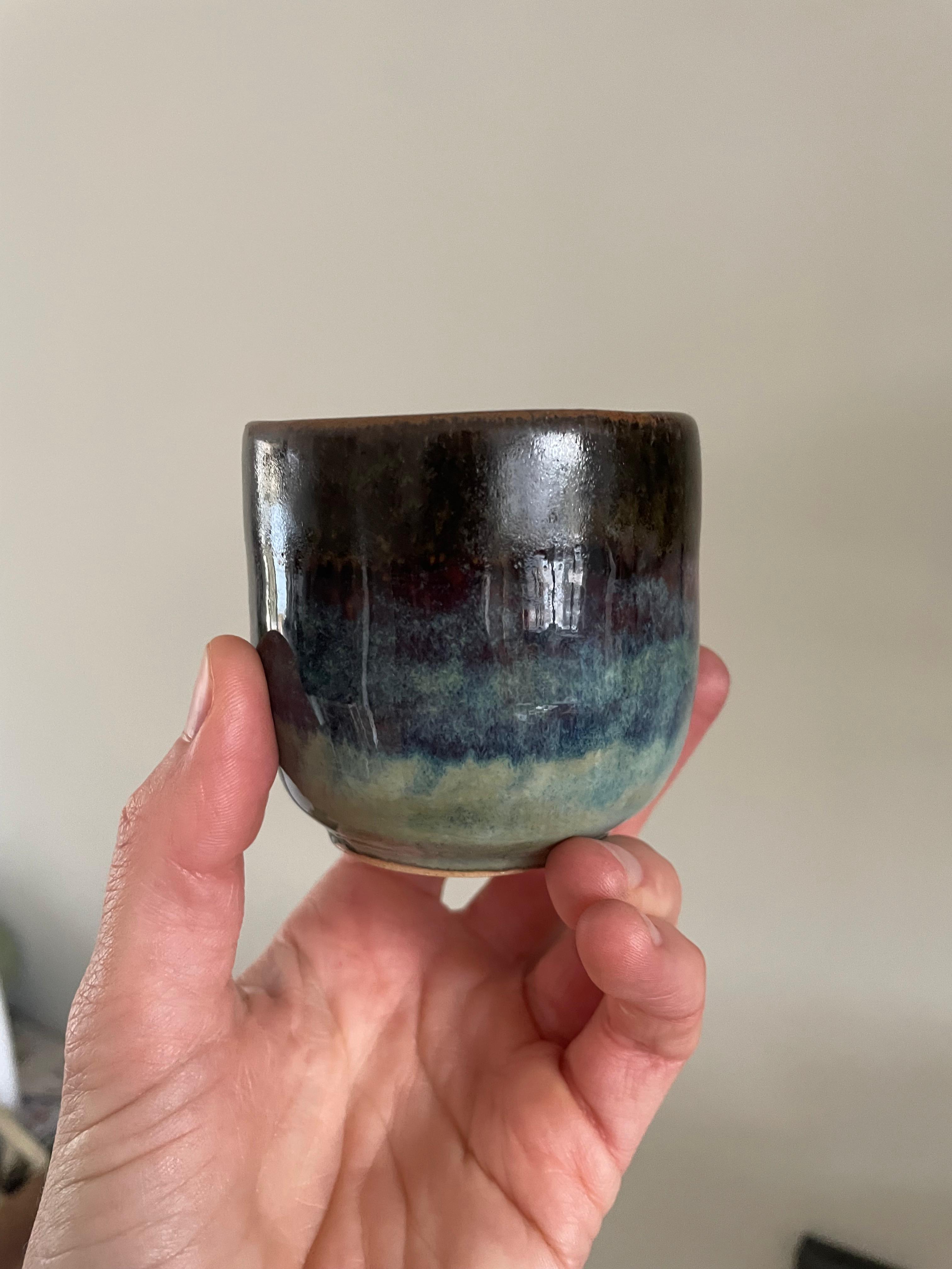 Dark glazed ceramic cup with blue and teal tones