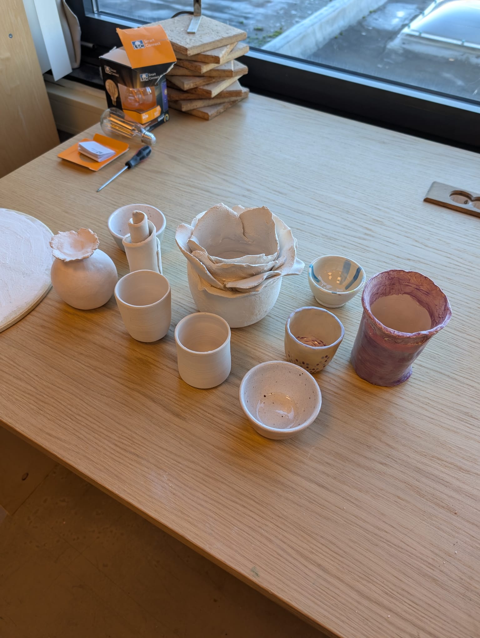 Collection of student pottery pieces including vases cups and bowls