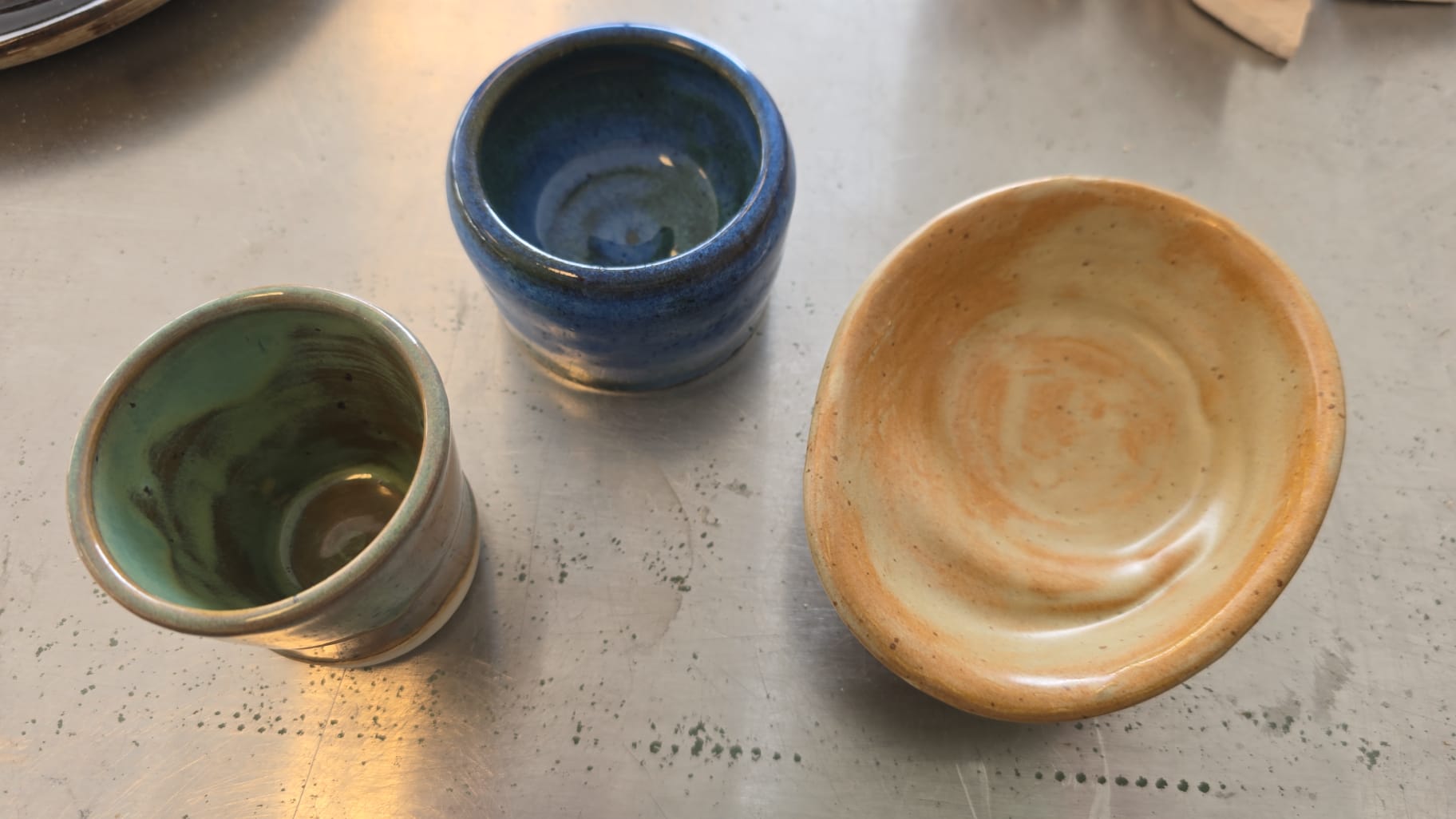 Glazed ceramic cups and bowl in green blue and amber tones