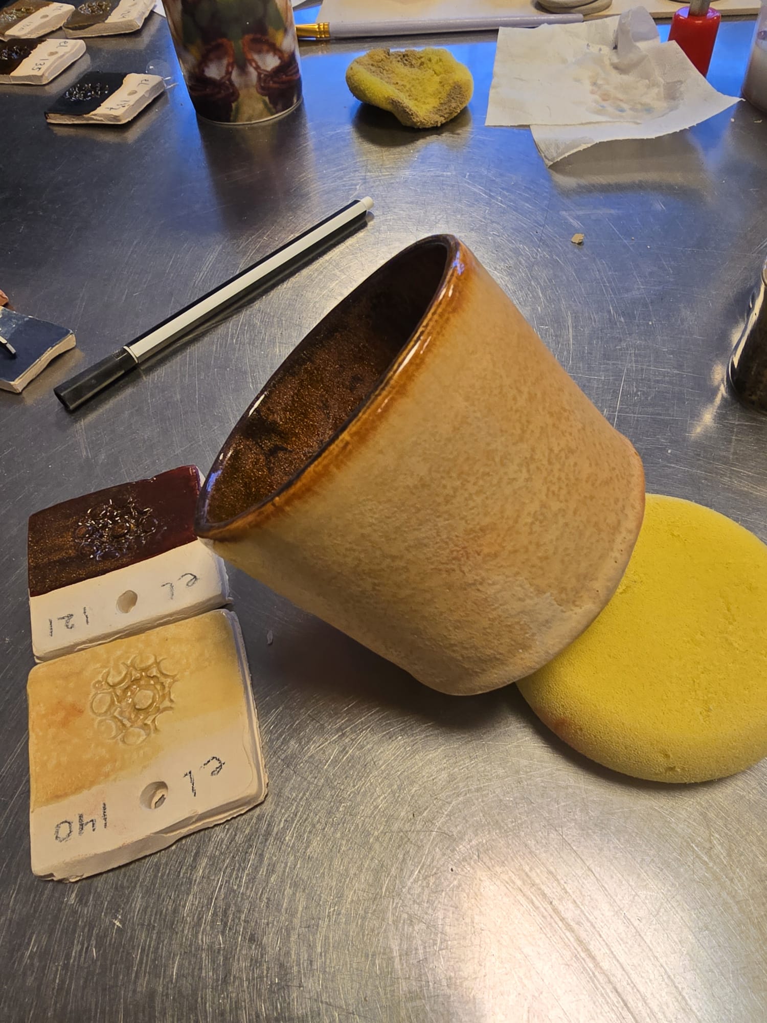 Amber glazed ceramic cup with glaze test tiles
